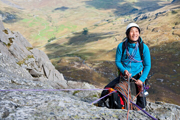 female rock climber at belay anchor point on Tryfan in North Wales