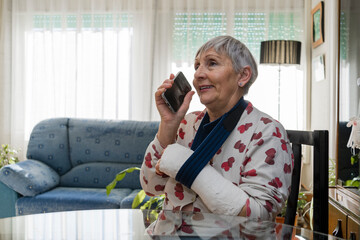 Caucasian white-haired elderly woman with broken arm, sitting at home