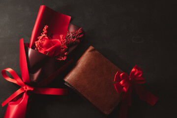 Top view a bouquet of roses and an empty wallet no money brown leather on black background;