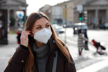 Close up of beautiful woman wearing FFP2 KN95 protective mask looking to the side in winter clothes outdoors