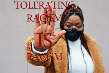 Tolerating racism is racism. African american woman, wear black face mask show stop hand sign.