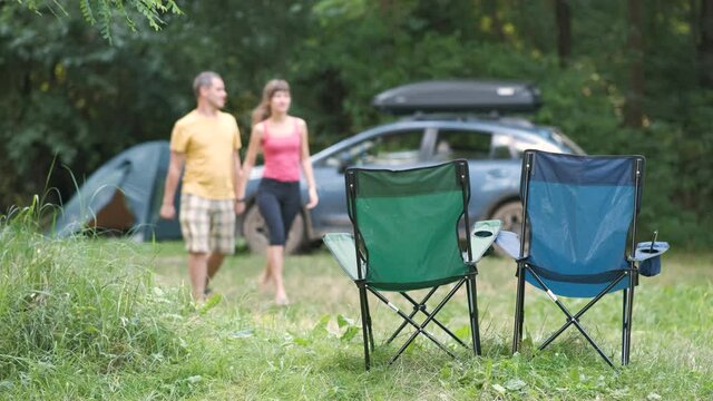 Happy active couple resting at campsite hugging and kissing happily near a car and a tent.