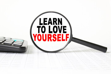 words LEARN TO LOVE YOURSELF in a magnifying glass on a white background. business concept