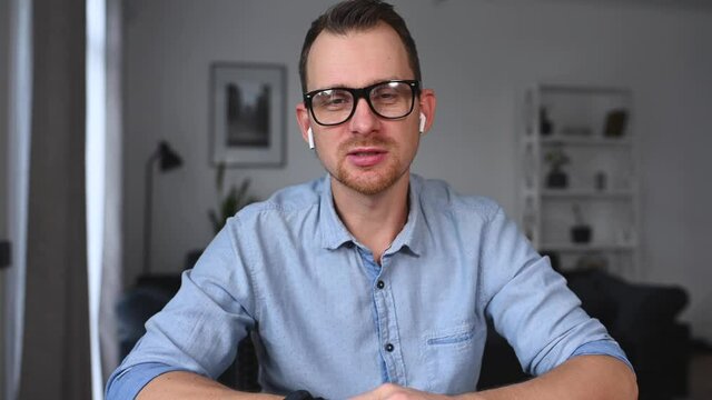 A young happy man in casual shirt talking via video call, mentor, trainer conducts webinar, online class. Video meeting, virtual conference with an intelligent guy, webcam video screen