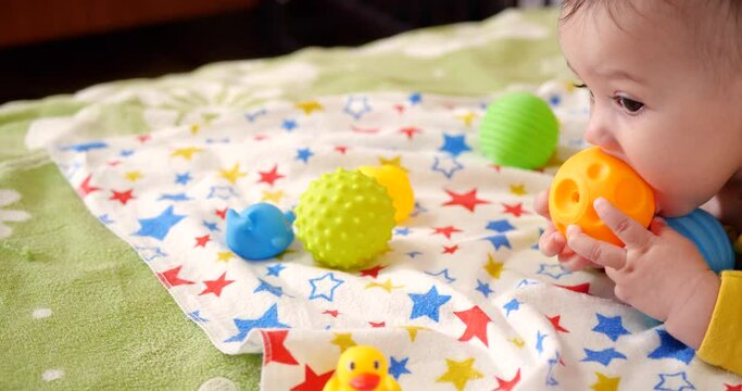 infant, childhood concept - close-up of smiling happy Baby plays with a teether. Teeth cutting. First teeth. Joy toothless 7 months baby bite, gnaws teether toy
