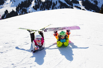 two female friends with ski and snowboard equipment posing on the snow.