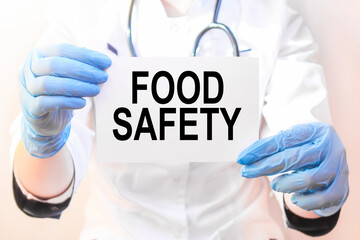 The doctor's blue - gloved hands show the word FOOD SAFETY - . a gloved hand on a white background. Medical concept. the medicine