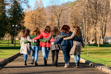 Young group of girls walking in autumn park, autumn clothes and autumn walk. Graduation from high school.