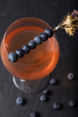 Sweet cocktail in goblet glass with fresh blueberries and dried flowers