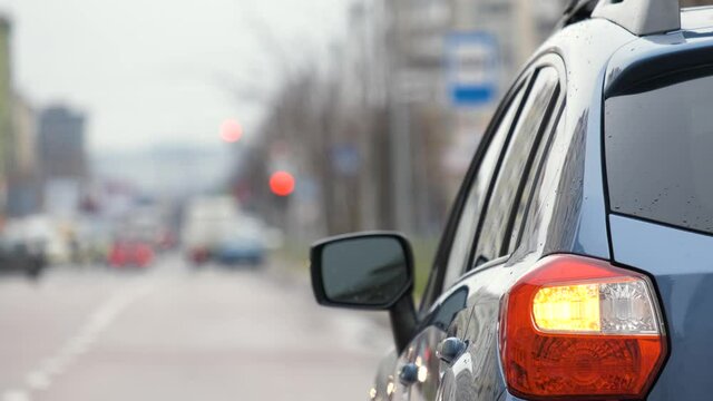 Closeup of rear lamp of a broken car parked on a city street side with blinking signal lights.