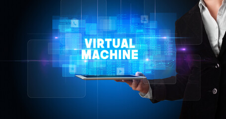 Young business person working on tablet and shows the inscription: VIRTUAL MACHINE