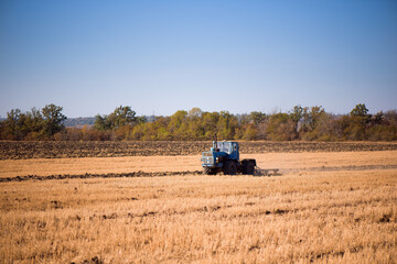 Obraz premium the tractor plows the field in autumn