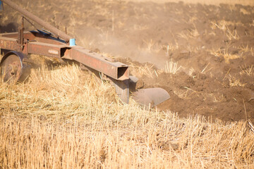 Agriculture blue tractor plowing in autumn on the field.