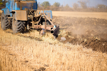 Fototapeta premium Tractor seeding directly into the stubble after the harvest with blue sky during autumn day.