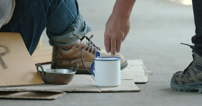 Homeless man sitting on sidewalk is getting coin money from people
