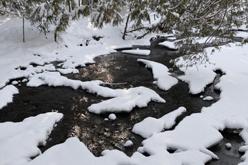 Fresh snow on rapids of Hewitts Creek after a snowstorm along Wilkins Walk Barrie Canada