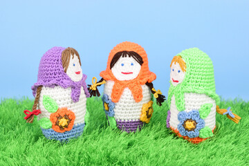 Obraz na płótnie Canvas Three knitted dolls stand opposite each other on green grass