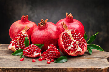 Several ripe pomegranate fruits and an open pomegranate with pomegranate leaves on a wooden old...