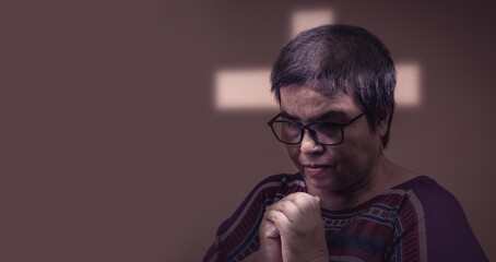 Crucifix-shaped light ray on woman face,christian concept,Prayer woman praise worship to GOD on dark background.