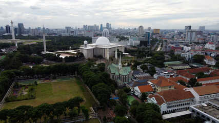 Aerial view of Jakarta cathedral and Istiqlal Mosque. It is the largest mosque in Southeast Asia and noise cloud with Jakarta cityscape. JAKARTA - Indonesia. January 30, 2021