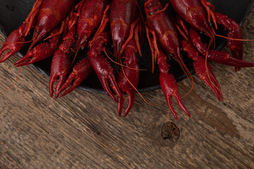 Boiled crayfish on black plate, shot from top on wooden table 