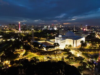 Obraz premium Aerial view of Istiqlal Mosque. It is the largest mosque in Southeast Asia and noise cloud at night with Jakarta cityscape. JAKARTA - Indonesia. January 30, 2021