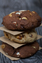 Oatmeal cookies with peanuts and chocolate. Folded in a column and laid out with paper. On pine boards.