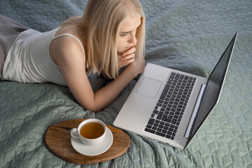 Woman using laptop on her bed