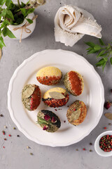 Easter eggs decorated with different spices and cereals without dyes and preservatives on a plate on a gray concrete background. View from above