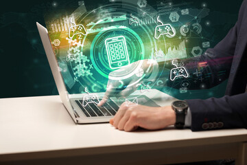 Business hand typing on a modern laptop with smartphone icon coming out from multimedia screen, intuitive technology concept