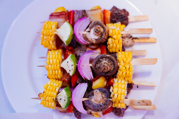 canapes of kebabs from vegetables, mushrooms, corn, onions in a white plate 