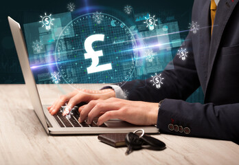 business hand working in stock market with pound icons coming out from laptop screen