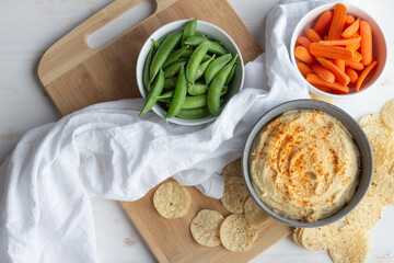 Fresh hummus with pea pods, carrot sticks and tortilla chips