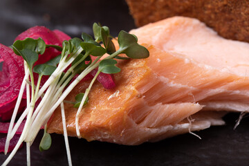 Oven cooked salmon  with marinated onions and bread crisps on black  plate 