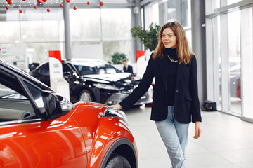 Fototapeta na wymiar Lady in a car salon. Woman buying the car. Girl in a black jacket.
