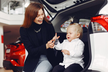 Fototapeta premium Family in a car salon. Mother with daughter. Lady in a black jacket.