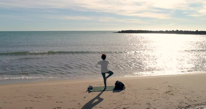 bella mujer madura realizando posiciones yoga junto al mar