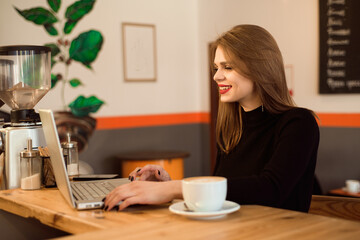 Beautiful Caucasian woman dreaming about something while sitting with portable net-book in modern cafe bar.
