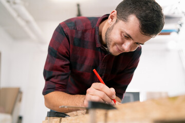 Exact measured. Close-up of young male carpenter making measurements on the wooden plank