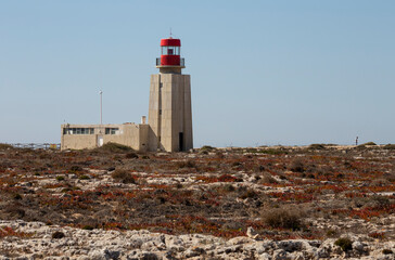 Fototapeta na wymiar Lighthouse on the rocky plateau in Sagres Cape, Algarve, Portugal.
