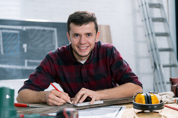 Portrait of a hardworking professional carpenter holding a angular ruler and pencil while measuring...