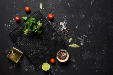 Black stone background with food, spices, vegetables, greens and oil. Ingredients for cooking. Top view, copy space.