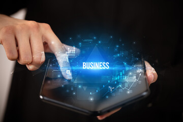 Businessman holding a foldable smartphone with BUSINESS inscription, business concept