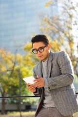 Fototapeta premium Young man reading a digital book using an e-reader on the street