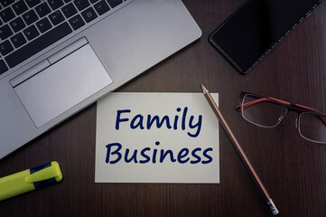Top view of laptop, phone, glasses and pencil with card with inscription family business.