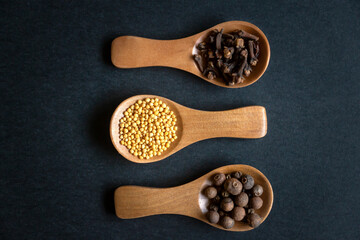 A set of various spices on wooden spoons and different surfaces.