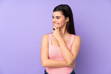 Young woman over isolated purple background looking to the side