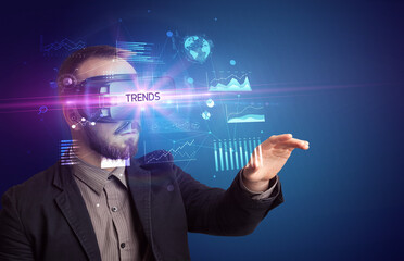 Businessman looking through Virtual Reality glasses with TRENDS inscription, new business concept