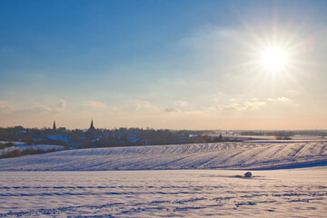 the catholic and protestant church of homberg in winter with snow and blue sky and sun	