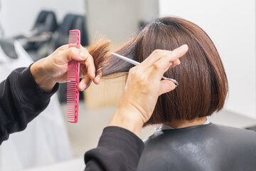 Naklejka premium ヘアサロンで髪の毛をカットする美容師の手元